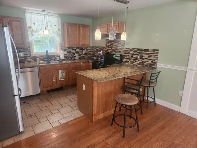 a kitchen with stainless steel appliances granite countertop a stove a sink dishwasher a refrigerator with a dining table and chairs