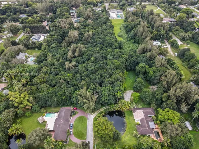 an aerial view of residential house with outdoor space and trees all around