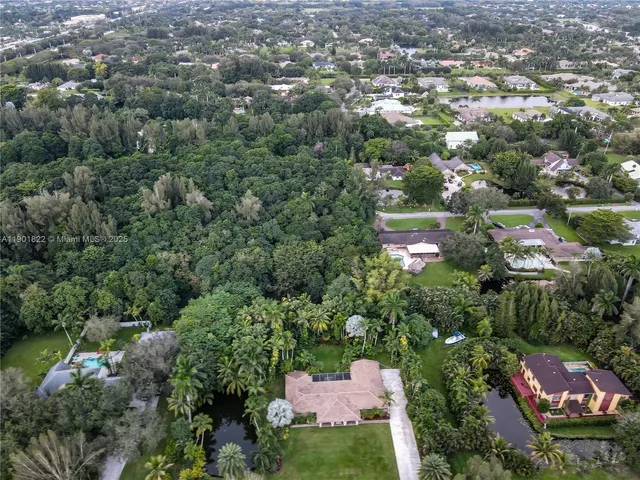 an aerial view of residential houses with outdoor space and trees