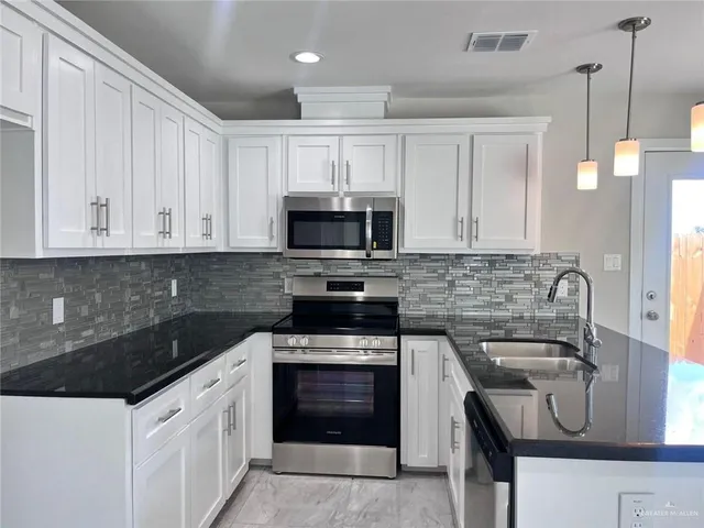 a kitchen with granite countertop white cabinets and stainless steel appliances