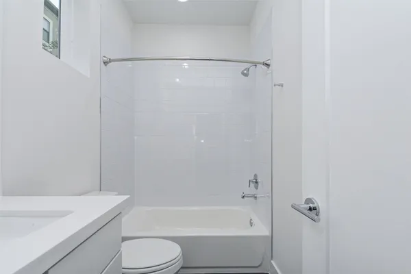 a bathroom with a bathtub shower sink vanity and toilet