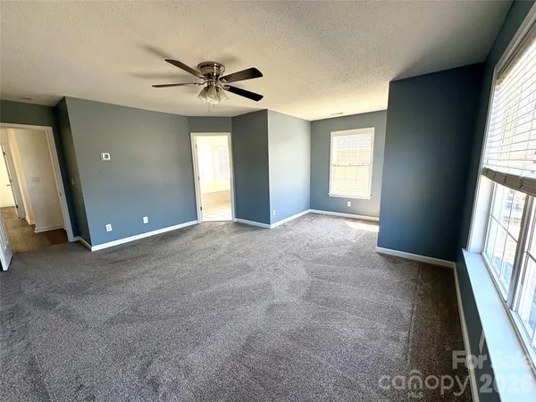 an empty room with windows and fan