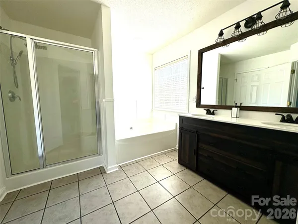 a bathroom with a double vanity sink a mirror and a bathtub