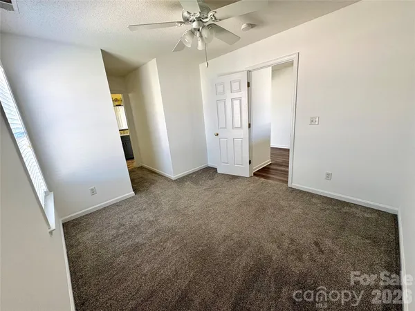 an empty room with windows and fan