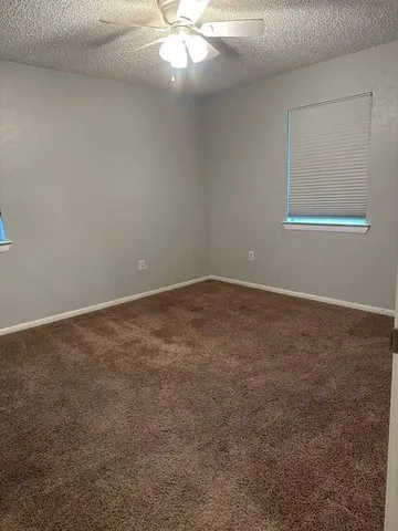an empty room with a chandelier fan and windows