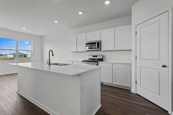 a kitchen with stainless steel appliances granite countertop a stove a sink and a microwave