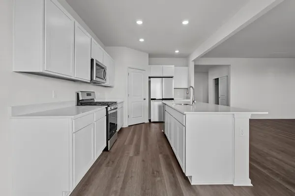 a view of kitchen and empty room with wooden floor