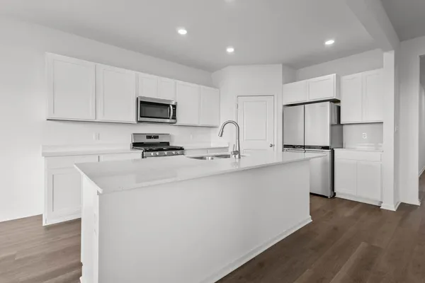 a kitchen with white cabinets stainless steel appliances and wooden floor