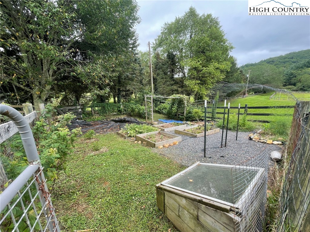 1453 Big Flatts Church Road Fleetwood, NC 28626 - Photo 47 of 50 a view of a backyard with table and chairs potted plants and large tree