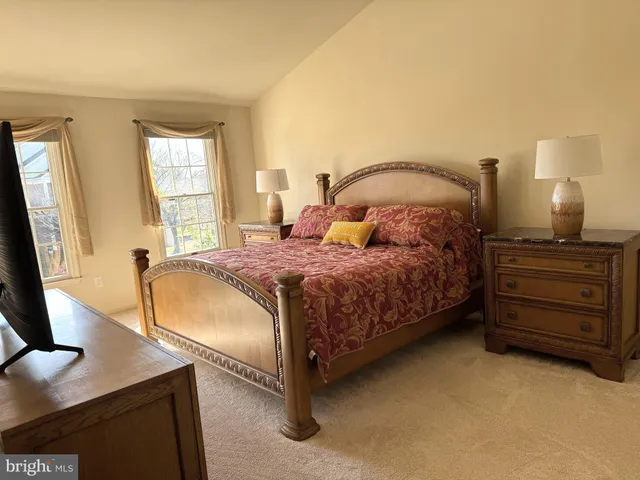 a bedroom with a bed and a flat tv screen on dresser