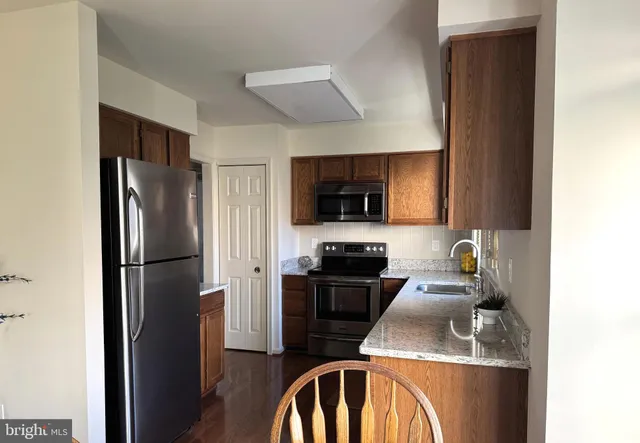 a kitchen with stainless steel appliances granite countertop a refrigerator a stove top oven a sink and dishwasher