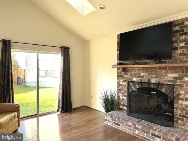 a living room with a fireplace a flat screen tv and a floor to ceiling window