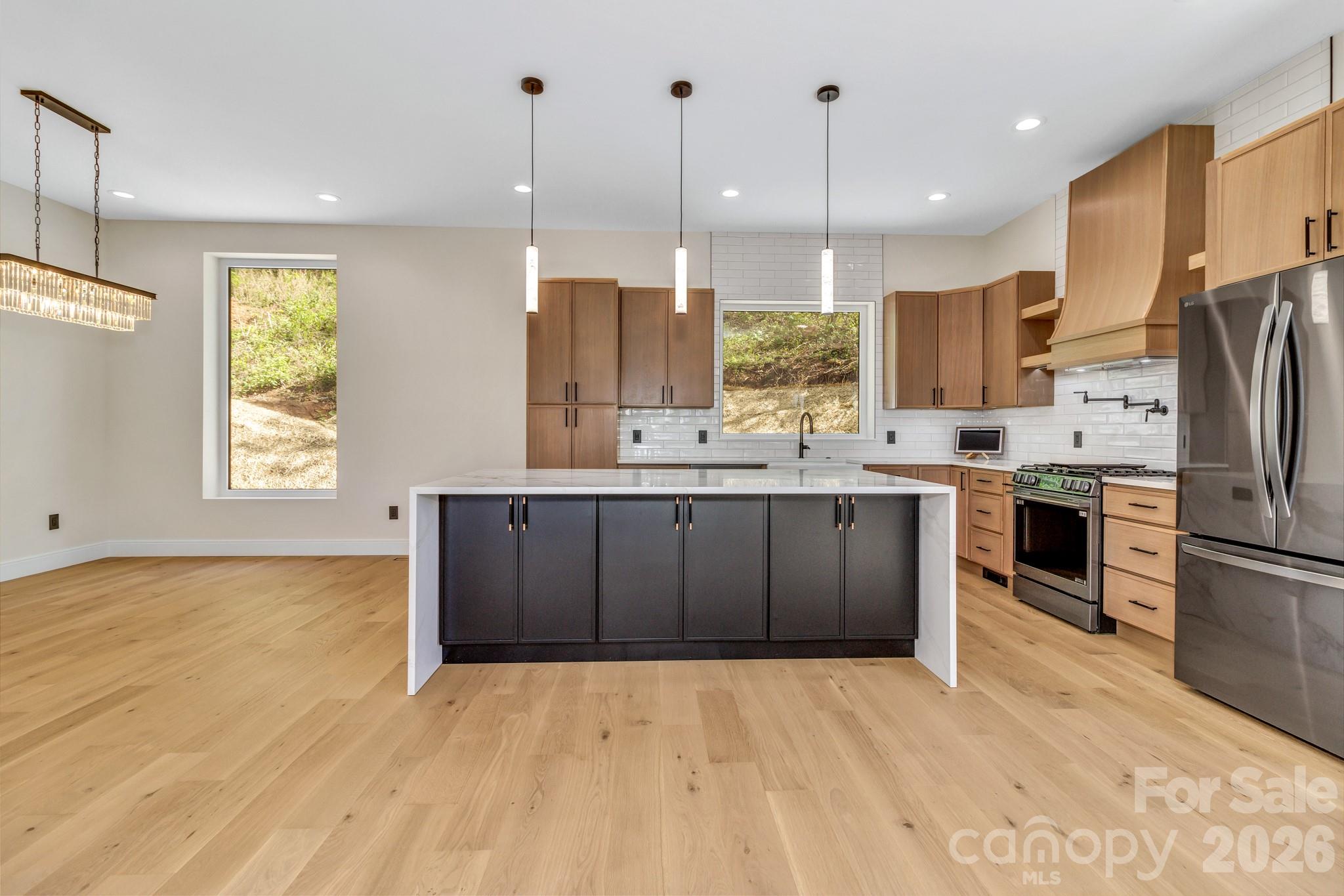 134 View Ridge Parkway Leicester, NC 28748 - Photo 10 of 48 a kitchen with stainless steel appliances kitchen island granite countertop a refrigerator a oven a sink with a dining table and chairs