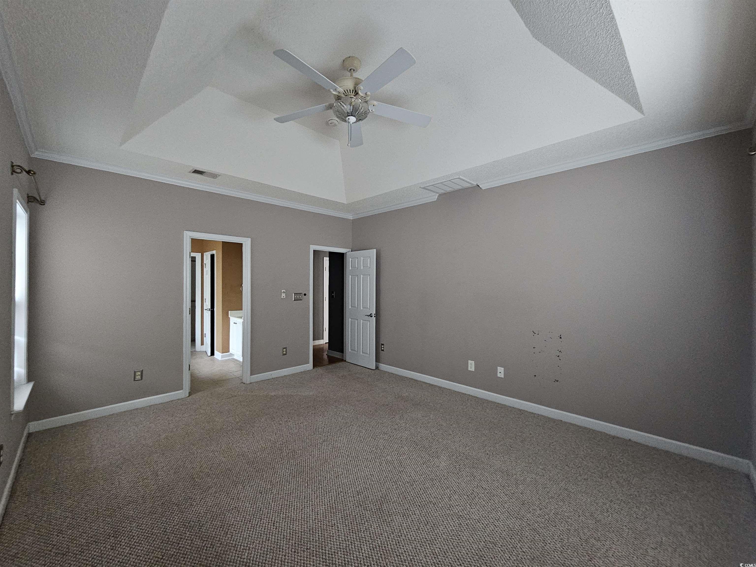 1011 Hillsdale Little River, SC 29566 - Photo 11 of 21 Unfurnished bedroom featuring a tray ceiling, carpet floors, a textured ceiling, ornamental molding, and a ceiling fan