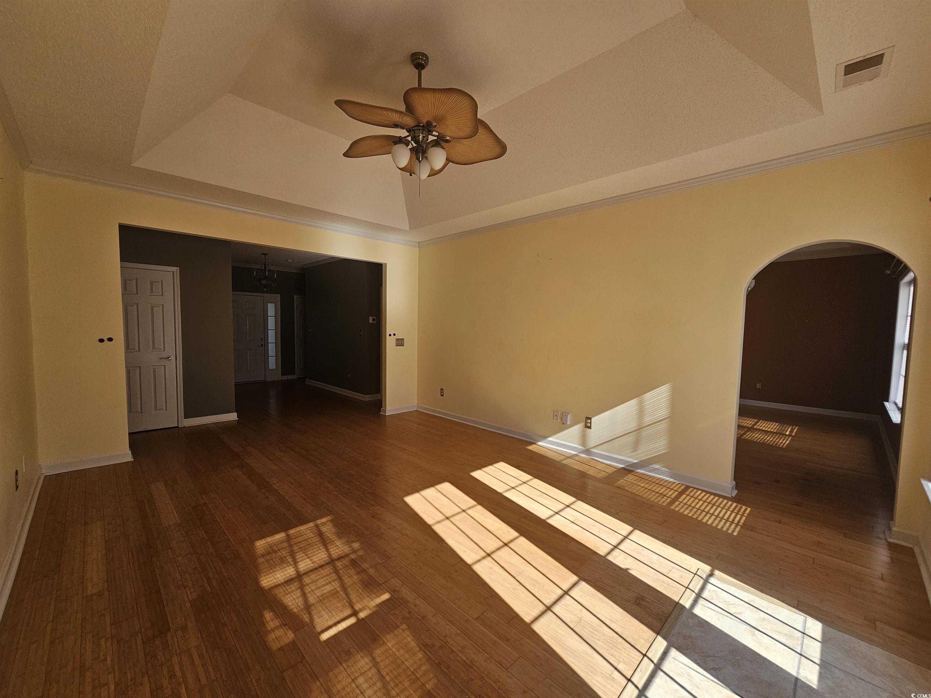 1011 Hillsdale Little River, SC 29566 - Photo 2 of 21 Spare room with hardwood / wood-style flooring, ceiling fan, a raised ceiling, arched walkways, and ornamental molding