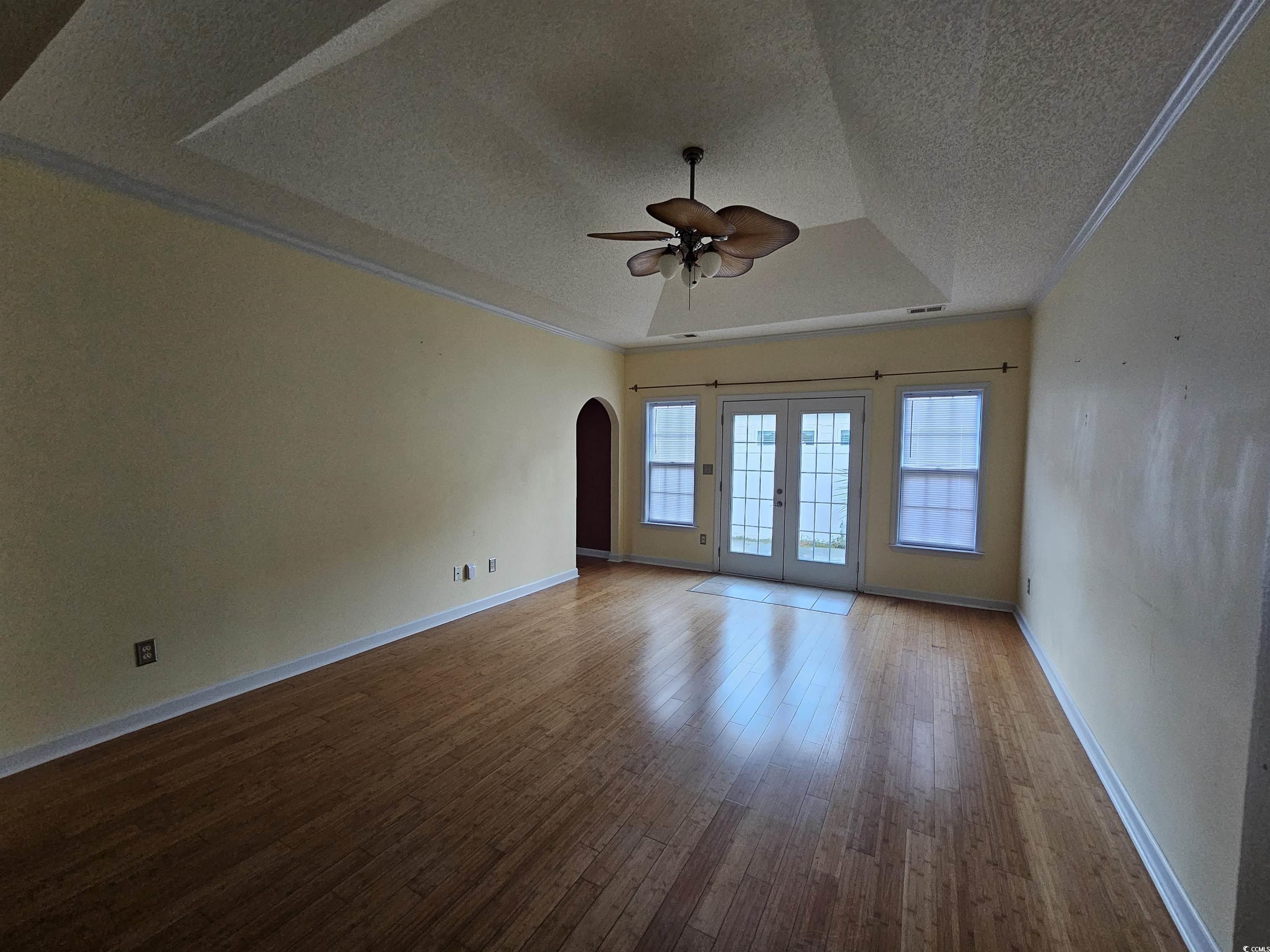 1011 Hillsdale Little River, SC 29566 - Photo 4 of 21 Unfurnished room featuring arched walkways, french doors, a raised ceiling, a textured ceiling, and dark wood-style flooring