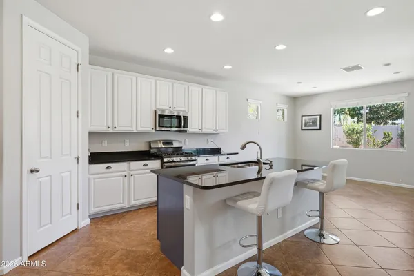 a kitchen with stainless steel appliances granite countertop a stove a sink a microwave a refrigerator and white cabinets