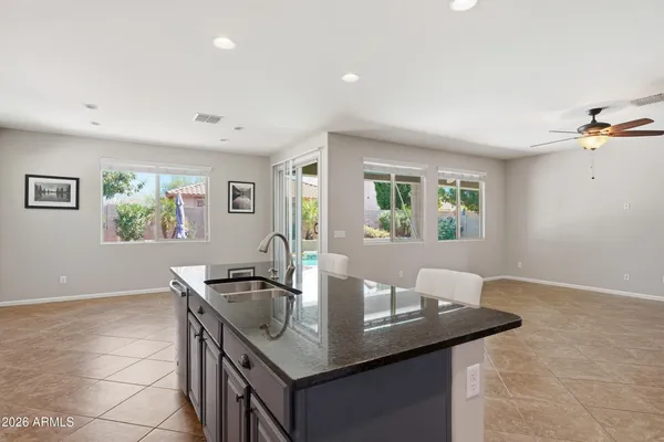 a dining hall with stainless steel appliances granite countertop a sink a table and chairs