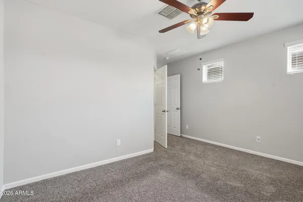an empty room with closet and a chandelier fan