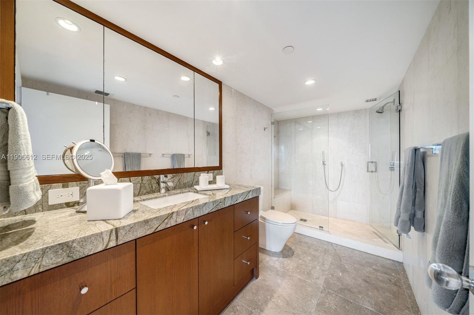 881 Ocean Drive, Unit 26B Key Biscayne, FL 33149 - Photo 24 of 34 a bathroom with a granite countertop sink mirror and shower