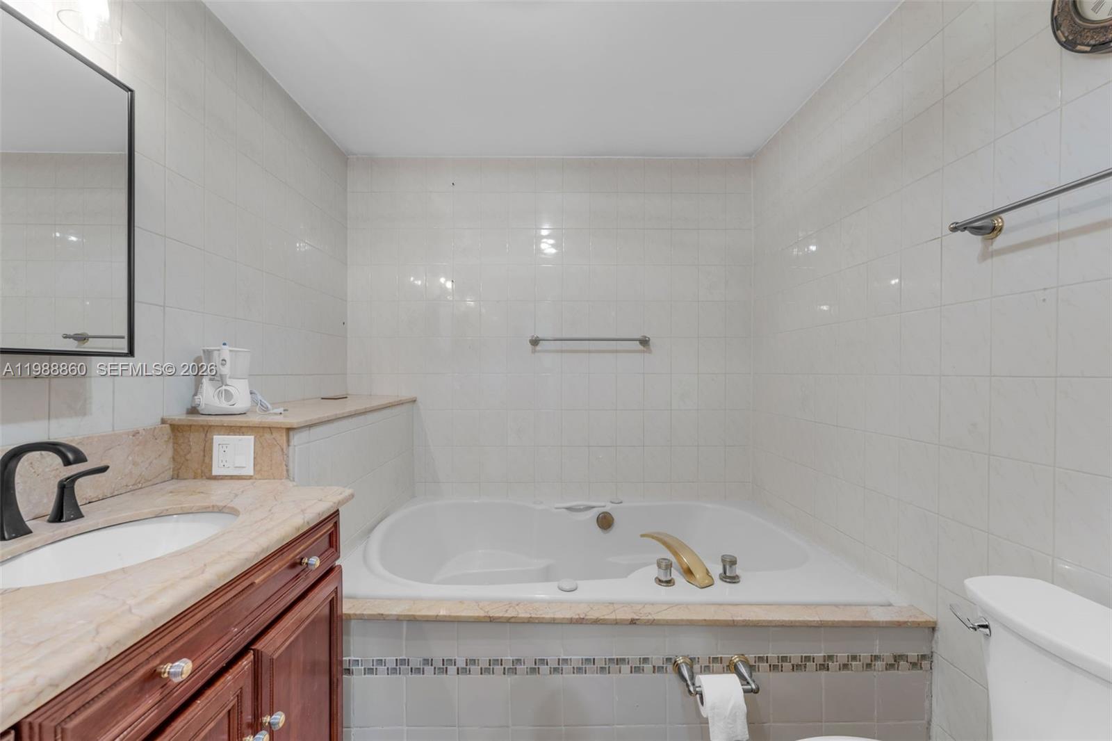10021 Southwest 145th Place Miami, FL 33186 - Photo 17 of 44 a bathroom with a granite countertop sink a mirror and a bathtub