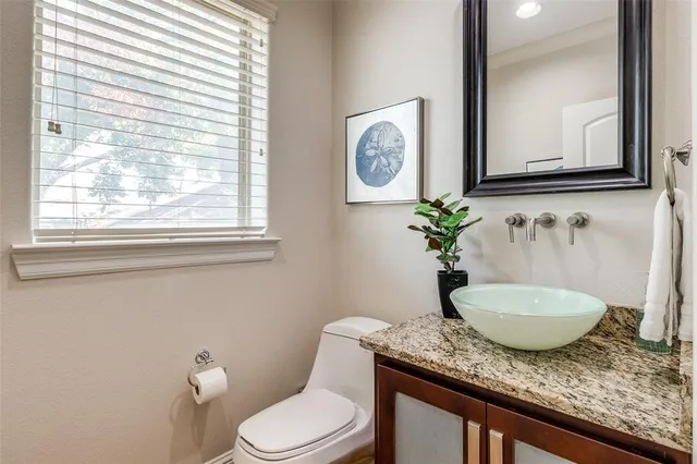 a bathroom with a granite countertop toilet sink and mirror