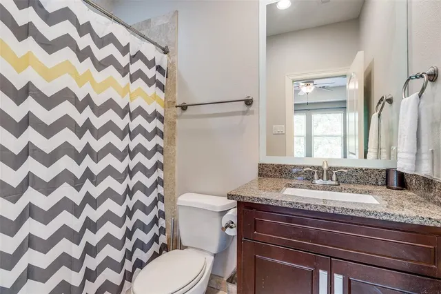 a bathroom with a granite countertop sink a toilet and a mirror