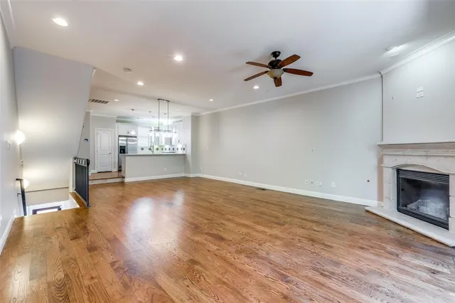 a view of a livingroom with a fireplace a ceiling fan and wooden floor