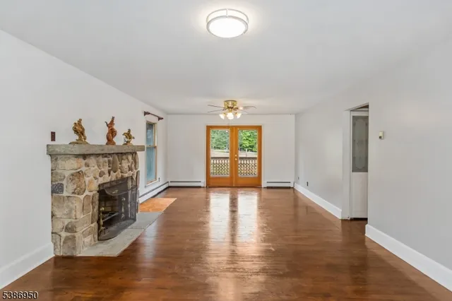 a view of a livingroom with wooden floor a fireplace and windows