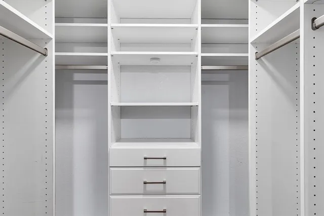 a view of walk in closet with empty racks