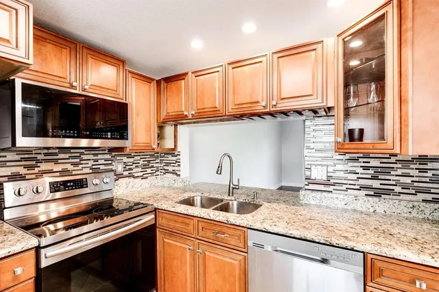a kitchen with granite countertop a sink a stove and cabinets