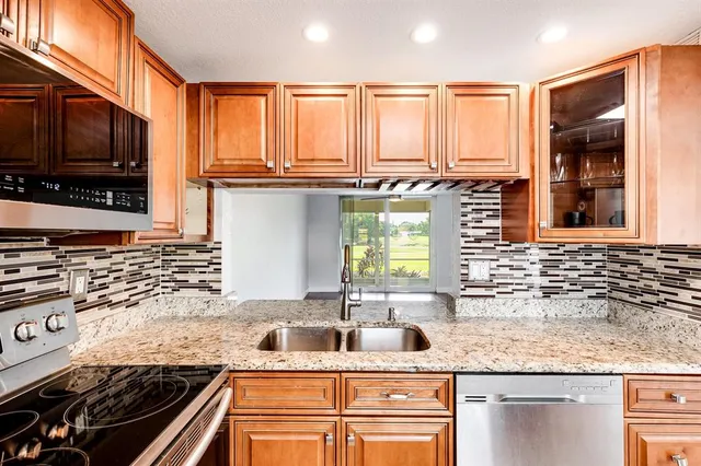 a kitchen with stainless steel appliances granite countertop a sink stove and cabinets