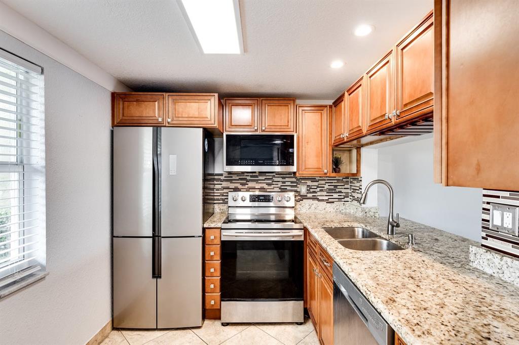 9080 Lime Bay Boulevard, Unit 109 Tamarac, FL 33321 - Photo 6 of 49 a kitchen with stainless steel appliances granite countertop a refrigerator sink stove and microwave