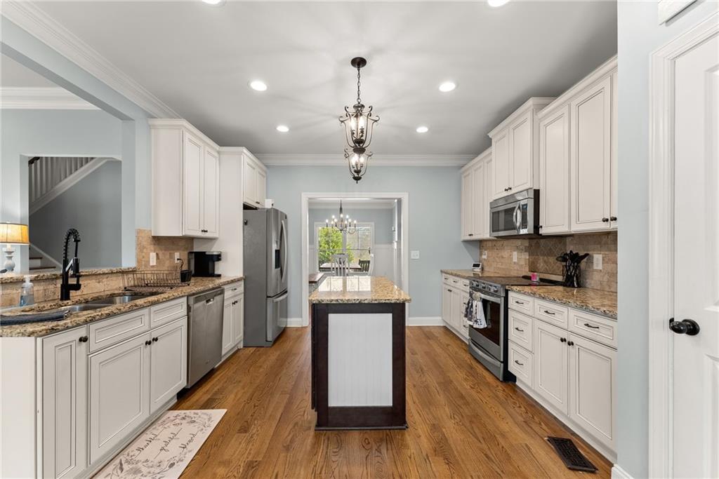 5716 Brickhampton Court Clermont, GA 30527 - Photo 11 of 42 a large kitchen with stainless steel appliances kitchen island granite countertop a stove a sink dishwasher and a refrigerator with wooden floor