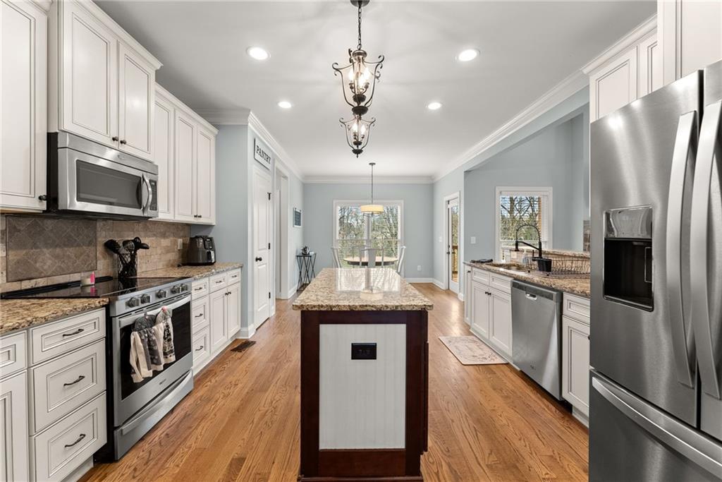 5716 Brickhampton Court Clermont, GA 30527 - Photo 13 of 42 a kitchen with stainless steel appliances granite countertop a refrigerator a stove a sink dishwasher a refrigerator and white cabinets with wooden floor