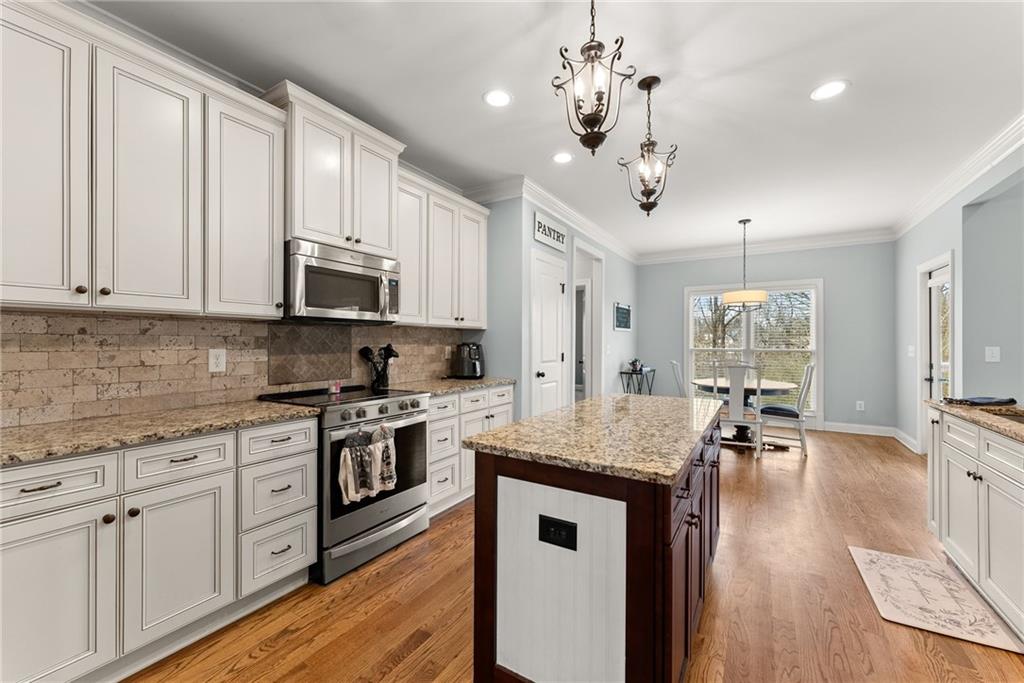 5716 Brickhampton Court Clermont, GA 30527 - Photo 14 of 42 a kitchen with stainless steel appliances granite countertop a sink dishwasher a stove and white cabinets with wooden floor