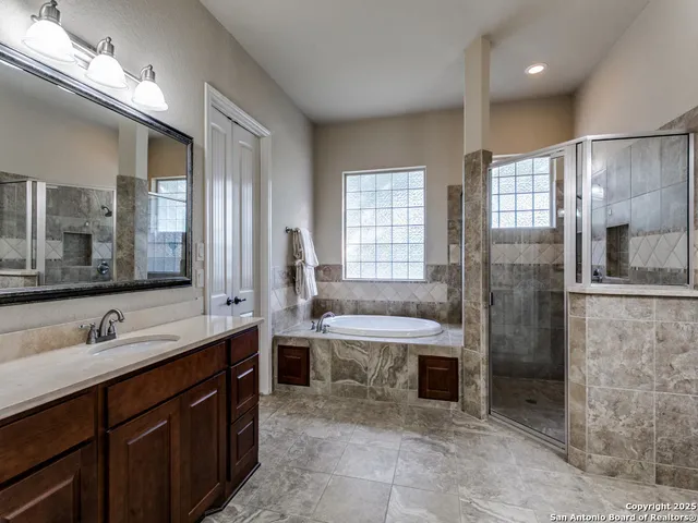 a large bathroom with a double vanity sink a large mirror and a bathtub