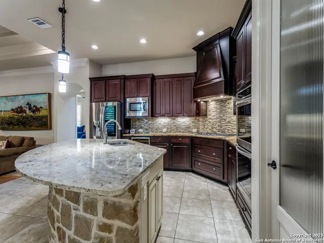 a kitchen with stainless steel appliances granite countertop a sink refrigerator and cabinets