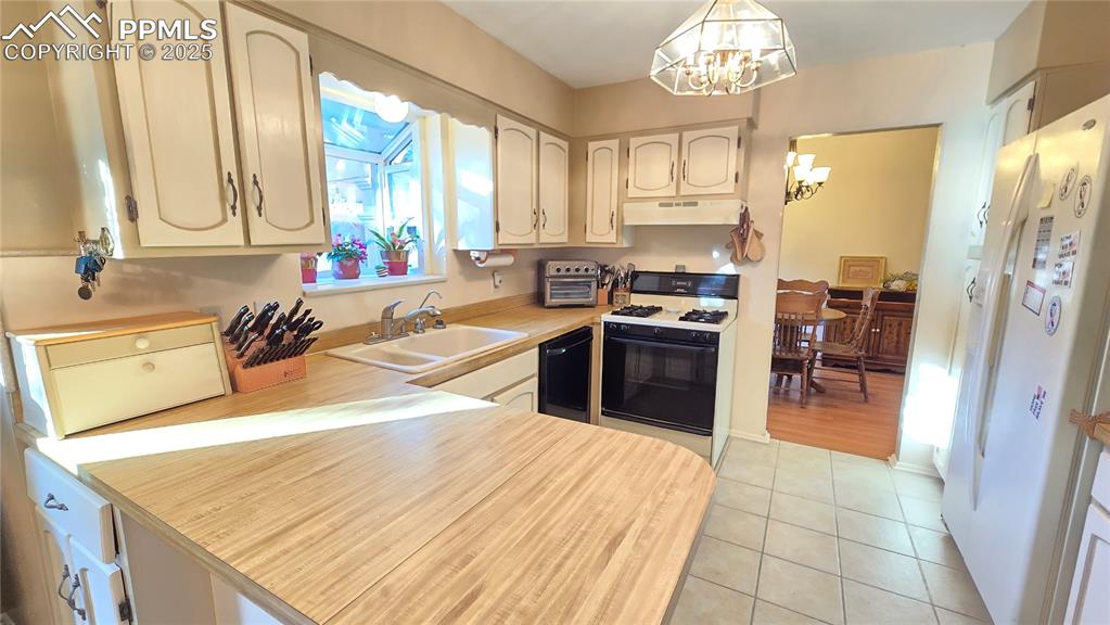 7231 South Webster Street Littleton, CO 80128 - Photo 19 of 44 Kitchen featuring light countertops, white fridge with ice dispenser, gas range oven, a chandelier, and light tile patterned floors