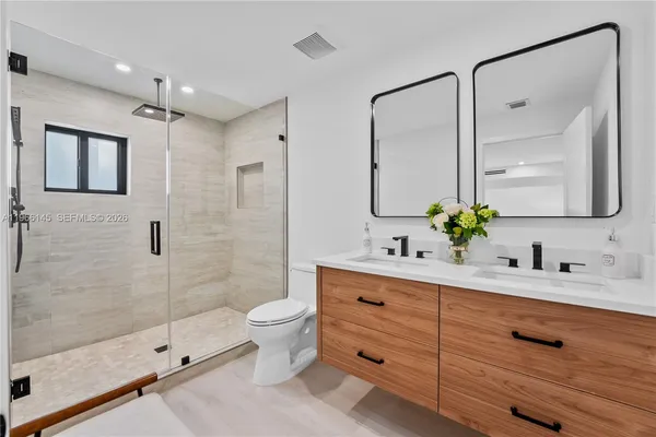 a bathroom with a double vanity sink toilet mirror and shower
