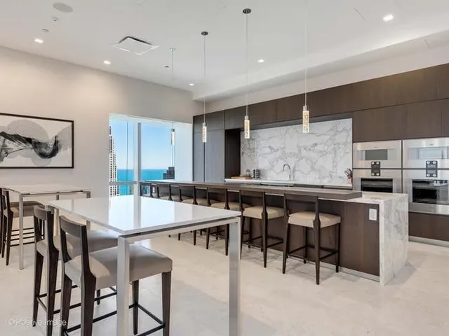 a kitchen with stainless steel appliances kitchen island granite countertop a table chairs sink and cabinets