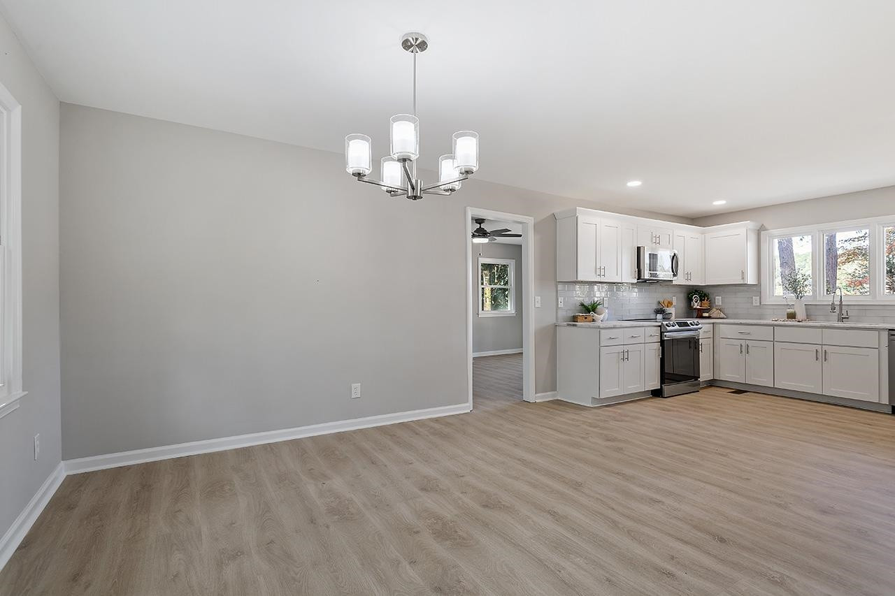 3420 Blue Ridge Road Raleigh, NC 27607 - Photo 12 of 36 a view of a kitchen with white cabinets stainless steel appliances and a chandelier