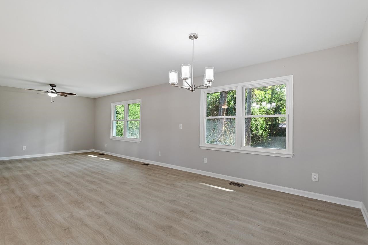 3420 Blue Ridge Road Raleigh, NC 27607 - Photo 15 of 36 an empty room with wooden floor a chandelier and windows