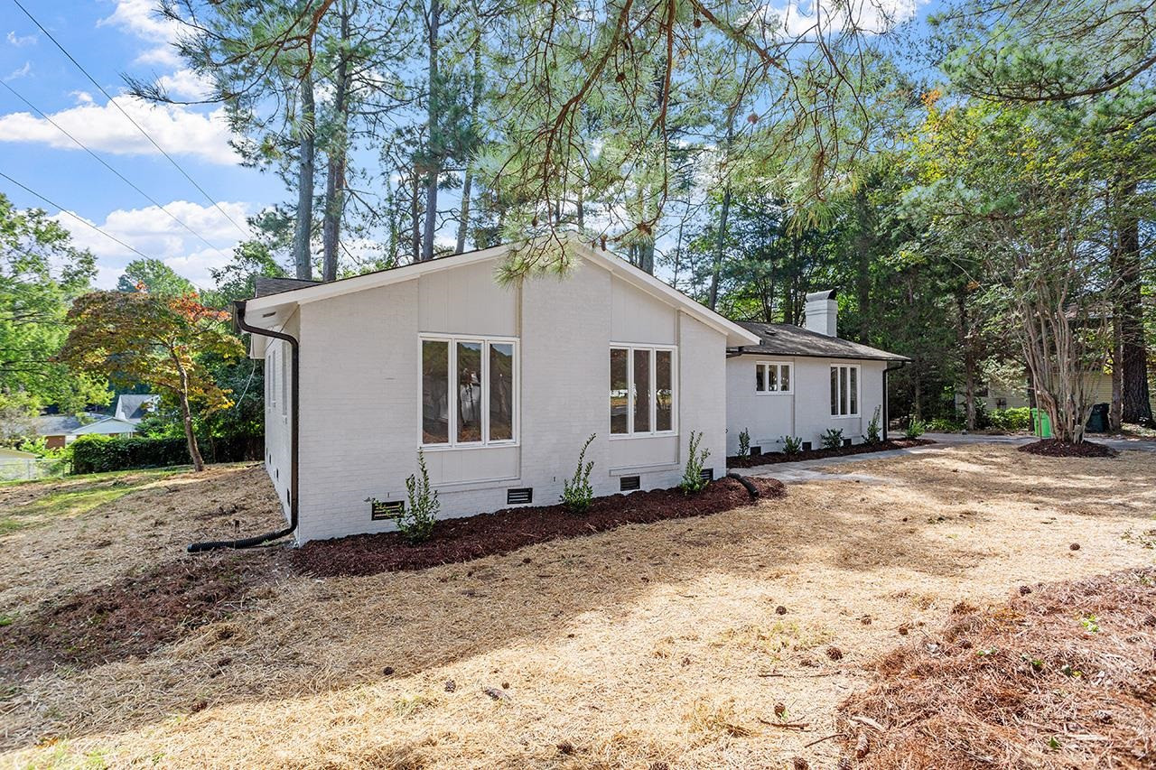 3420 Blue Ridge Road Raleigh, NC 27607 - Photo 30 of 36 a view of a white house with a yard covered in the forest