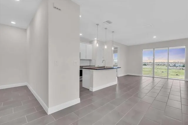 a view of an empty room with kitchen and stove top oven