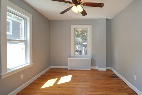 a view of empty room with wooden floor and fan
