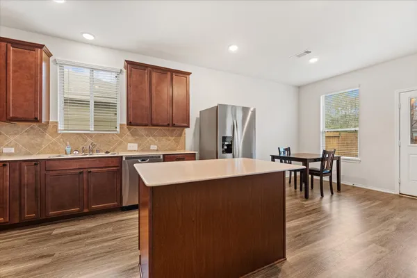 a kitchen with stainless steel appliances granite countertop wooden floors a stove a sink a dining table and chairs