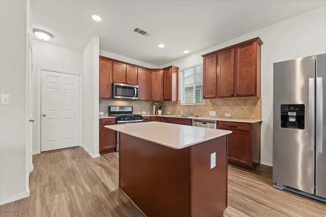 a kitchen with stainless steel appliances granite countertop a refrigerator a stove a sink and a microwave oven with wooden floor