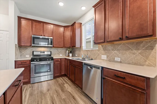 a kitchen with granite countertop wooden cabinets stainless steel appliances and a sink