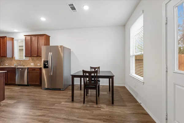 a kitchen with stainless steel appliances a refrigerator a stove a dining table and chairs with wooden floor